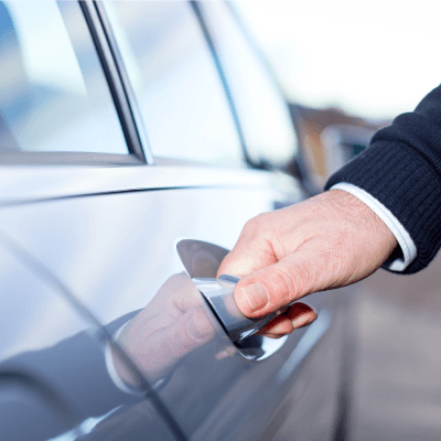 A suited chauffeur opening the door of a sedan