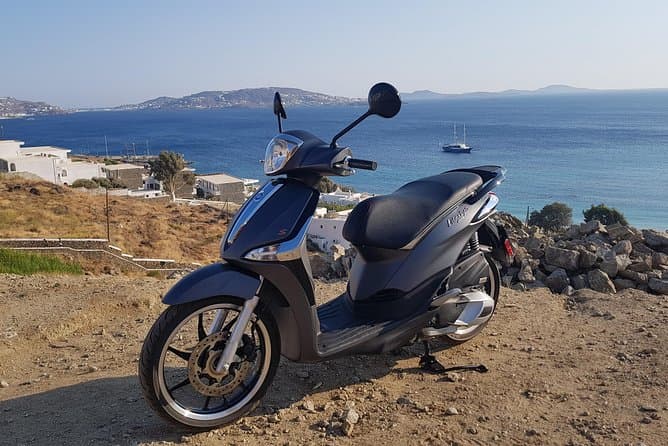 A rental scooter parked at a lookout above the bay of Mykonos Town